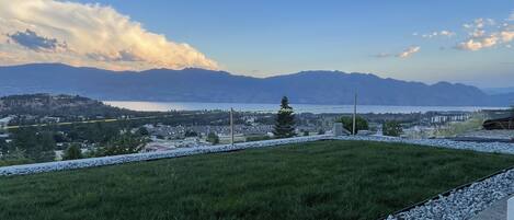 A grassy area with a view of mountains and a body of water in the distance.