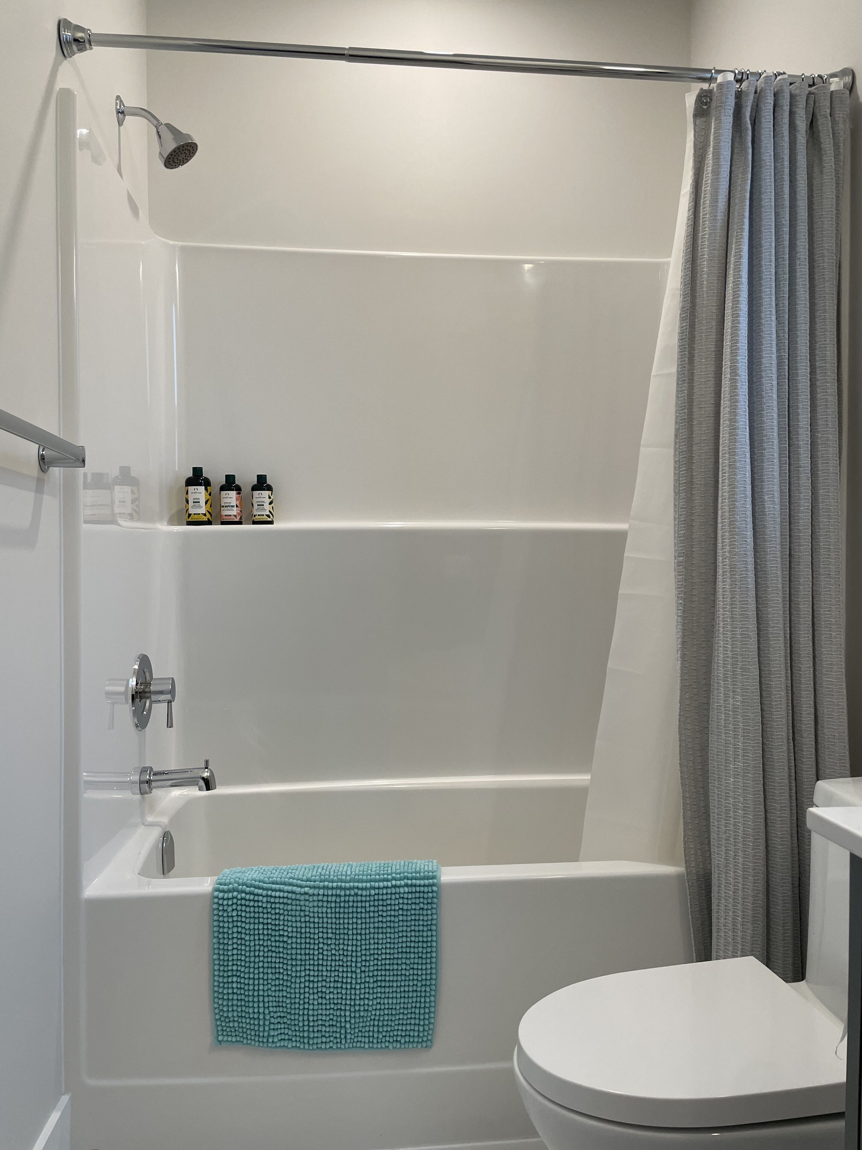 A modern bathroom with a bathtub, shower, and toilet.