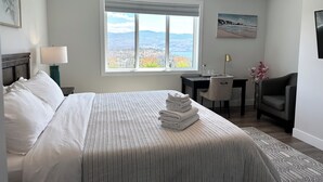 Een hotelkamer met een bed, een bureau, een stoel en een groot raam met uitzicht.