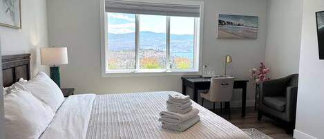 Habitació d'hotel amb llit, escriptori, cadira i una finestra gran amb vistes.
