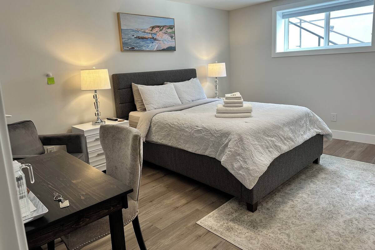 Un dormitorio moderno con cama, lámparas de noche, escritorio y una silla.
