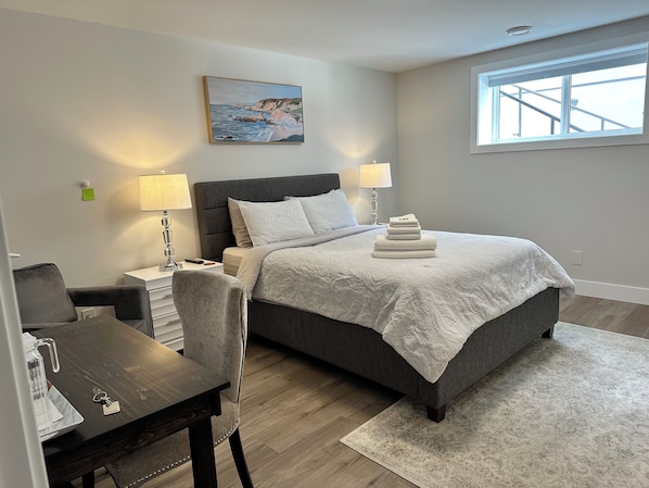 A modern bedroom with a bed, bedside lamps, a desk, and a chair.