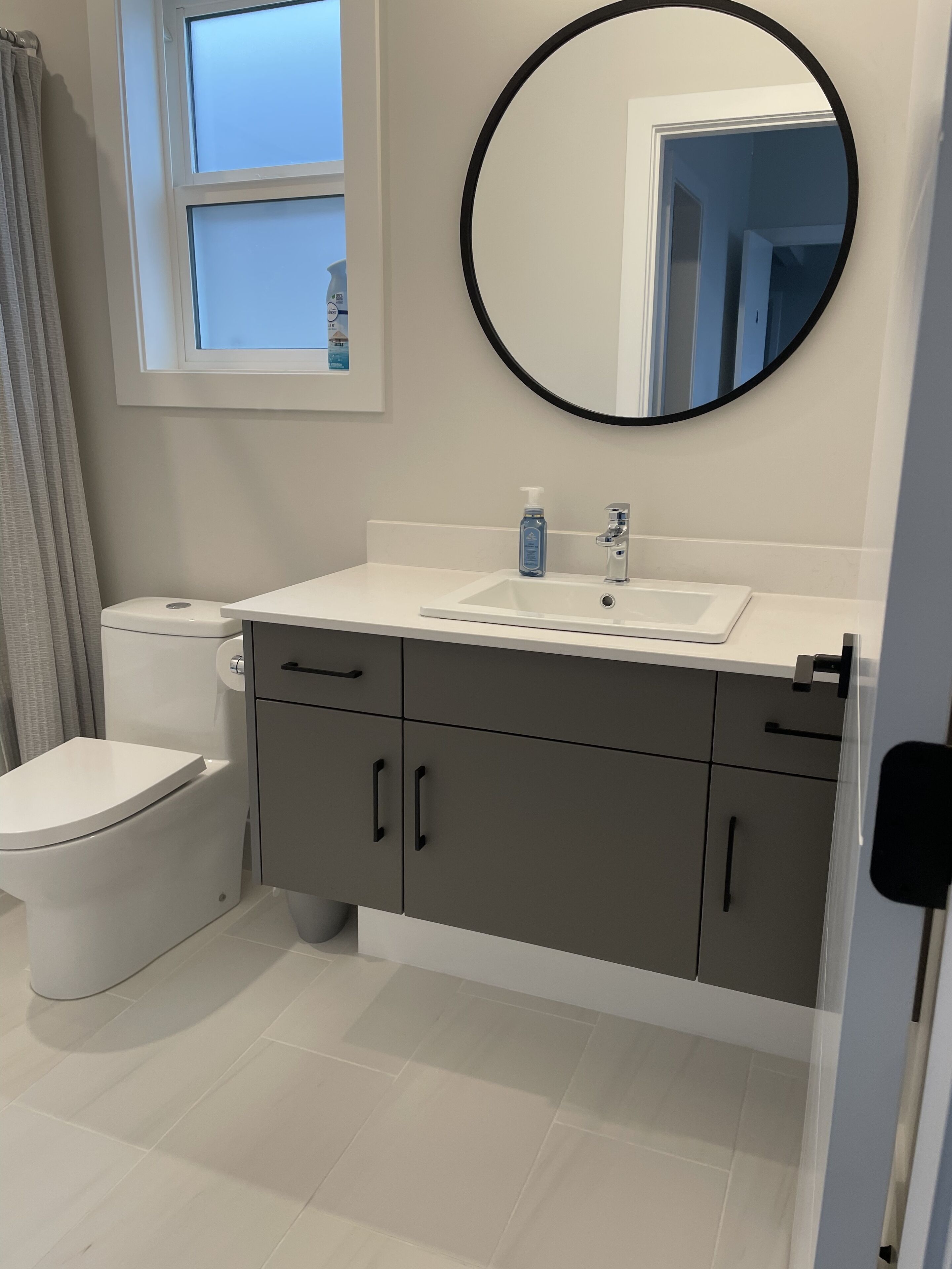 A bathroom with a toilet, a sink with a mirror, and a window above the sink.