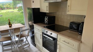 A kitchen with a dining area, a refrigerator, a stove, and a toaster. - Riverbank Cottage Lake District, Double Balcony (Egremont)