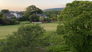 A view from a window overlooking a green landscape with trees and houses. - Riverbank Cottage Lake District, Double Balcony (Egremont)