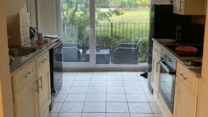 A kitchen with an archway leading to a balcony with a view of a green landscape. - Riverbank Cottage Lake District, Double Balcony (Egremont)