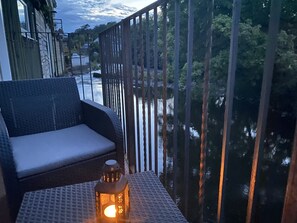 Een balkon met een rieten bank en een lantaarn.