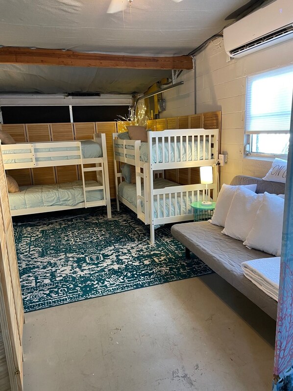 A room with bunk beds, a sofa, a patterned rug, and a window with blinds. - Private Home on Deep Salt Water Canal With Direct Gulf Access (Hernando Beach)