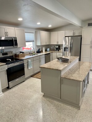 A modern kitchen with stainless steel appliances, a granite countertop, and light-colored cabinetry. - Private Home on Deep Salt Water Canal With Direct Gulf Access (Hernando Beach)
