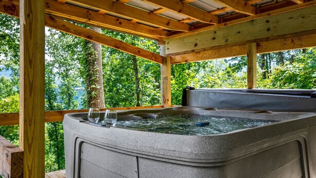 Un jacuzzi en una terraza de madera con vistas a un bosque.