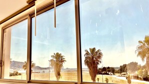 Ein Zimmer mit großem Fenster und Blick auf Strand und Palmen.