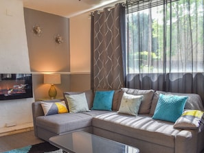 A modern living room with a sectional sofa, a flat-screen TV, and a glass coffee table. - Huddersfield House, Wood View (Huddersfield)