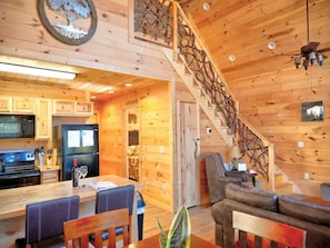 A wooden interior with a kitchen, dining area, and staircase.
