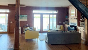 A spacious living area with a wooden floor, a staircase, and a view of the outdoors. - Sunsets on Water - private beach, pier, boat dock, fishing -12m to Navarre Beach (Navarre)