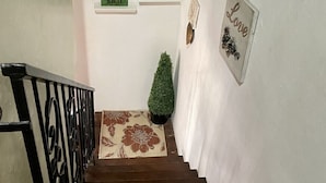 En trappe med gelænder i sort farve, en lille plantekasse og et billede i ramme på væggen.