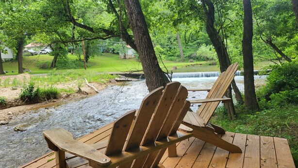 A wooden deck with Adirondack chairs overlooking a stream and a waterfall. - ❤️ Tiny House with Creek Access ❤️ (Anderson)