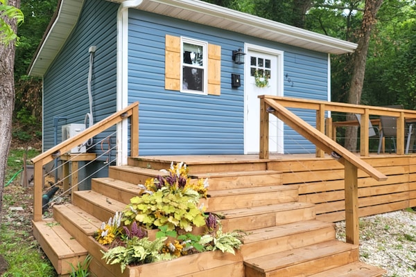 The humble blue tiny house meets you with its wrap around deck.
