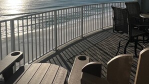 Un balcón con vista al océano, una mesa y dos sillas.