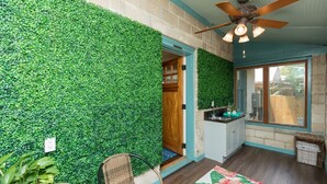 A room with a green wall, wooden door, ceiling fan, and a window with a view. - “Steeped in History” Exquisite 1919 Craftsman (Saint Augustine)