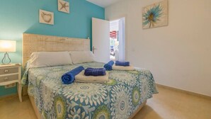 Un dormitorio con una cama, una mesita de noche, una puerta y una pared decorada con una pintura de una estrella de mar y una flor.