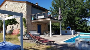 Edifici de pedra amb un balcó, terrassa exterior i piscina.