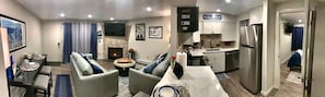 A modern living room with a fireplace, dining area, and kitchen.