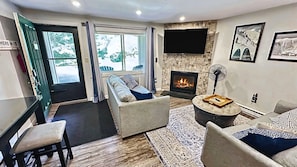 A living room with a fireplace, seating area, and a view through a door.