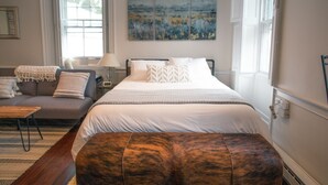 Un dormitorio con cama, sofá, lámpara y un cuadro en la pared.