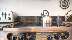 Una cocina con estufa de acero inoxidable, hervidor y tostadora.