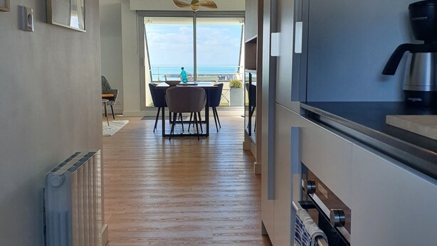 Eine moderne Küche mit Meerblick, Holzboden und einem Essbereich mit Tisch und Stühlen.