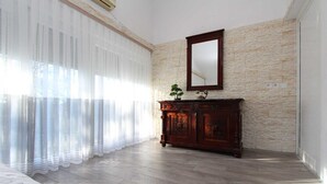 A room with a wooden cabinet, a large mirror, and a stone-textured wall. - HAWAII One-Bedroom Apartment 7 (Banjole)