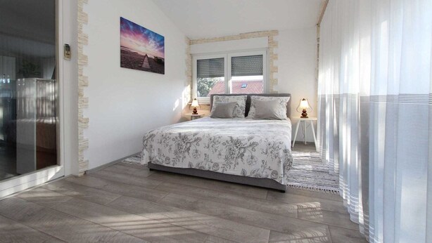 A bedroom with a bed, a window, a nightstand, and a picture on the wall. - HAWAII One-Bedroom Apartment 7 (Banjole)