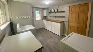 A laundry room with a washing machine, dryer, and cabinets. - Homey Houghton Haven (Roscommon)
