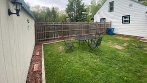 A backyard with a fenced area, a small patio table, and chairs. - Homey Houghton Haven (Roscommon)