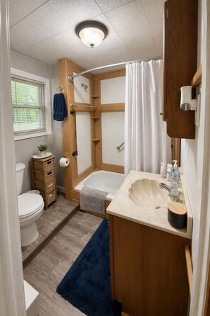 Een kleine badkamer met toilet, wastafel en bad.