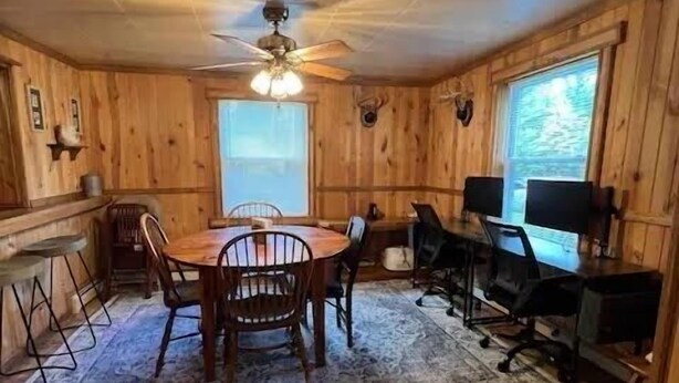 A wooden room with a dining table, chairs, a computer desk, and a ceiling fan. - Homey Houghton Haven (Roscommon)