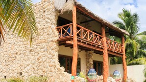 A stone building with a wooden balcony and a thatched roof. - Villa Marcela (Chetumal)