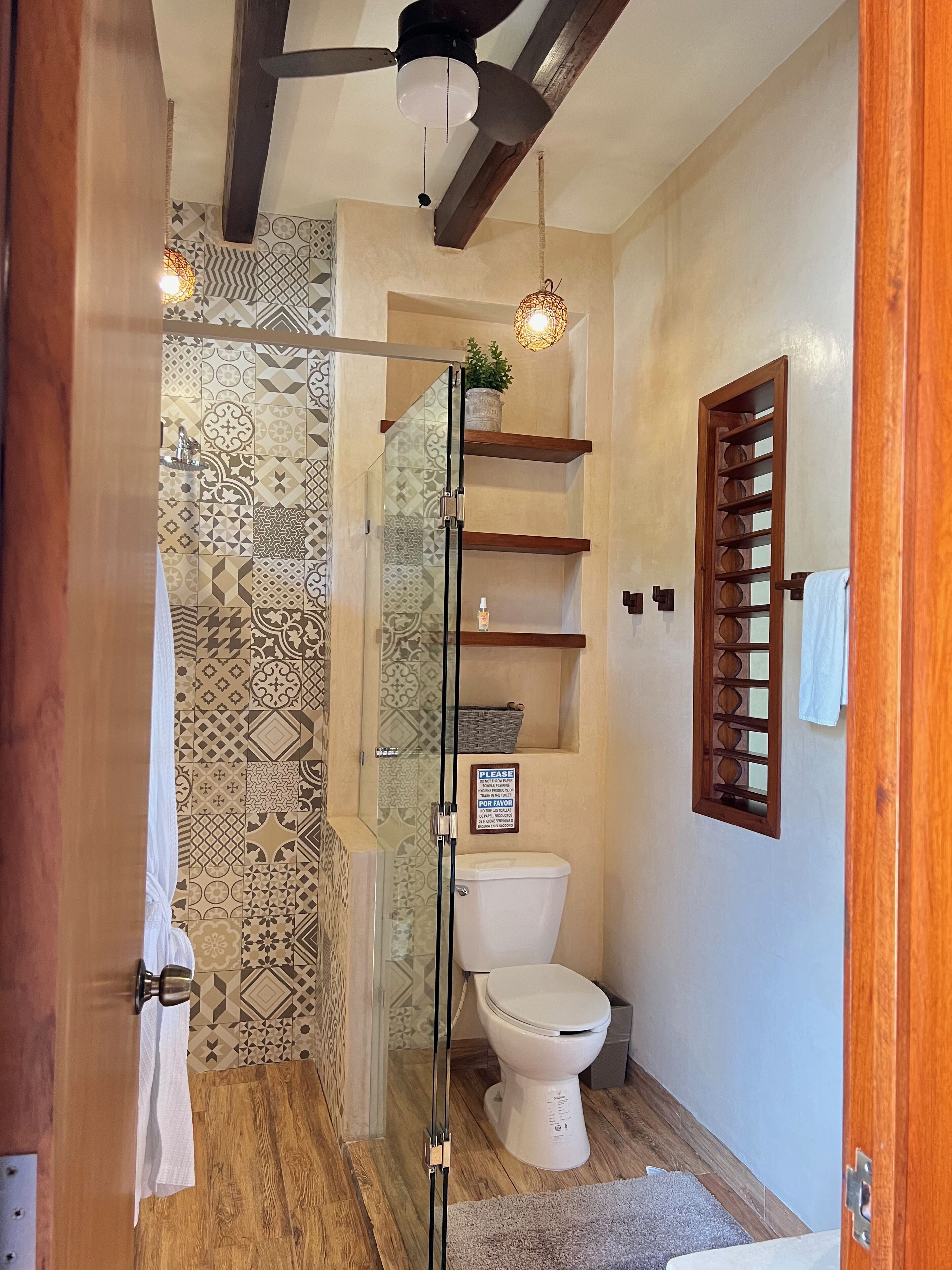Un baño con ducha, inodoro y ventilador de techo.