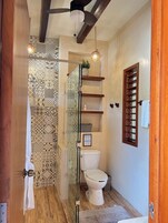 Un baño con ducha, inodoro y ventilador de techo.