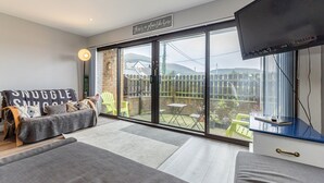 A cozy living room with a large sliding glass door leading to a backyard. - Central Apartment 3B (Newcastle)