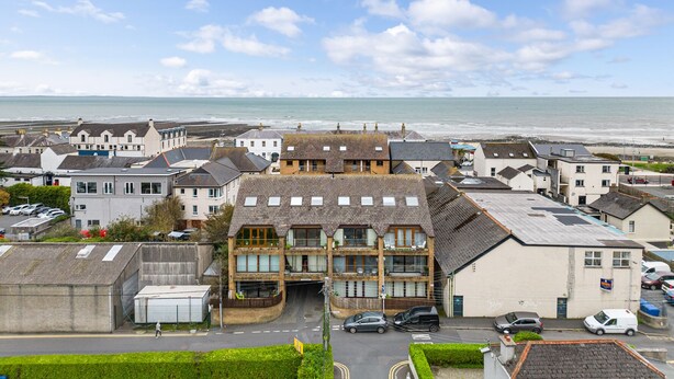 A coastal town with a mix of residential and commercial buildings, a clear view of the sea, and a pedestrian pathway leading to the beach. - Central Apartment 3B (Newcastle)
