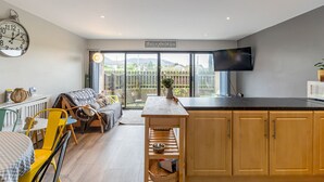 A modern kitchen with a large window, a flat-screen TV, and a cozy seating area with a sofa and chairs. - Central Apartment 3B (Newcastle)