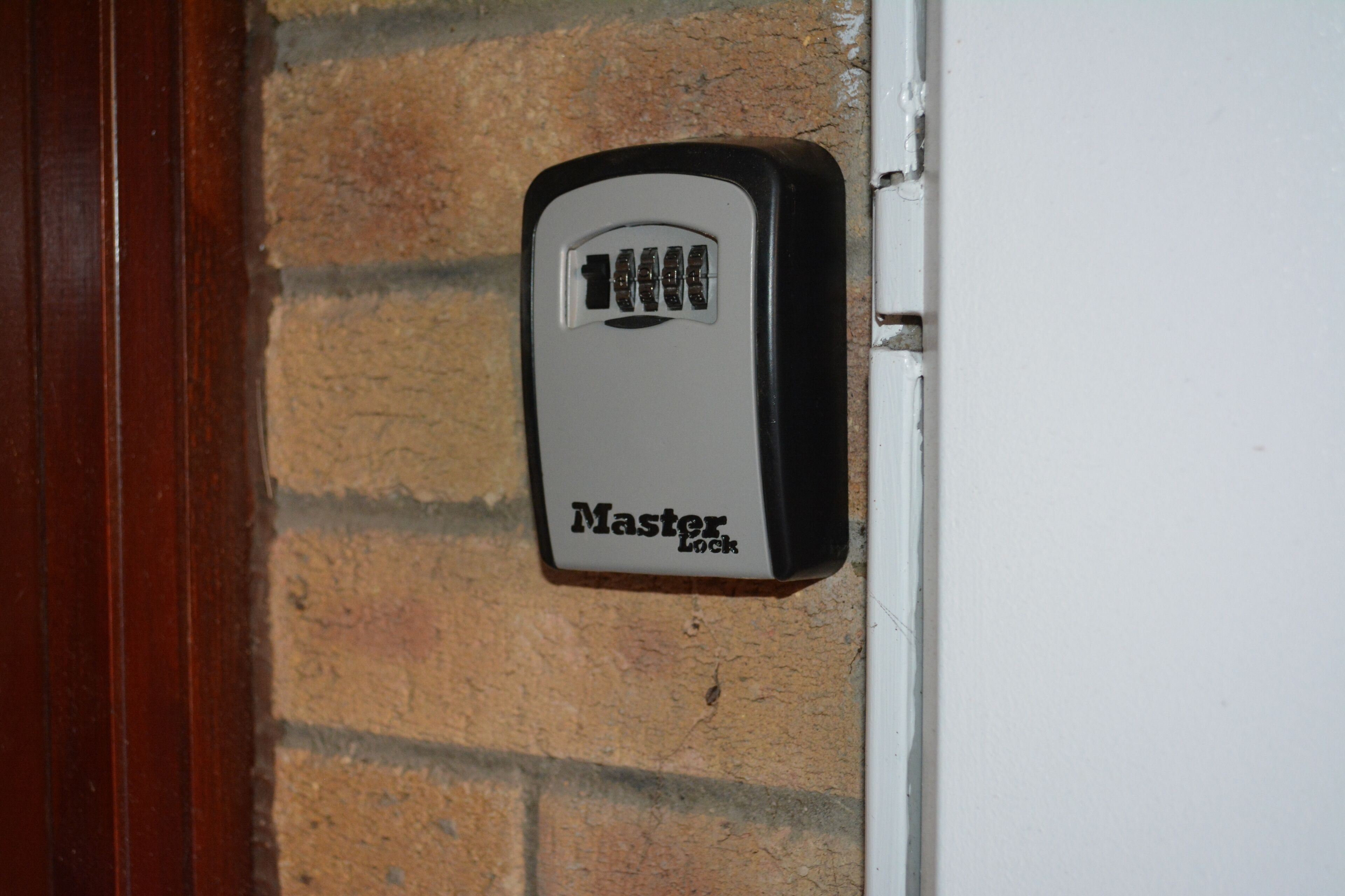 A door with a Master Lock device installed on a brick wall.
