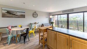 A kitchen with a dining area, a clock, and a view of a garden. - Central Apartment 3B (Newcastle)