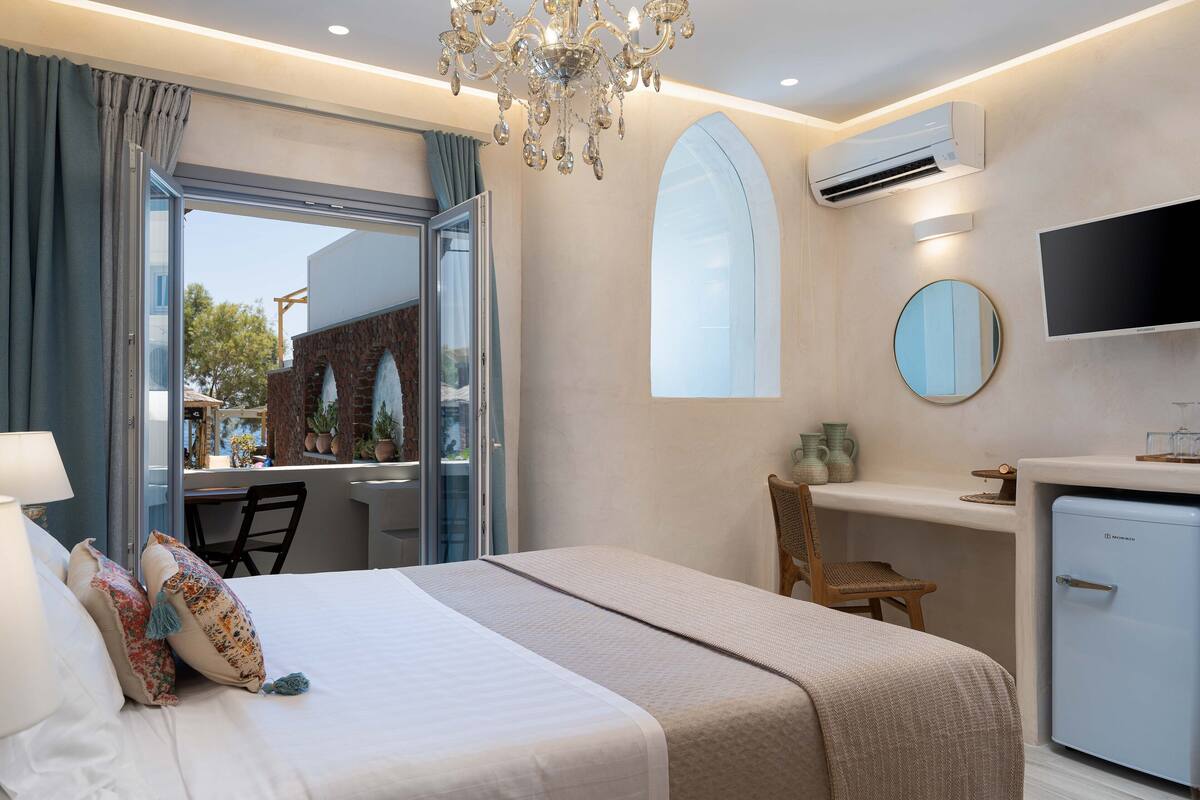 Una habitación de hotel con cama, escritorio, silla, televisor y aire acondicionado.