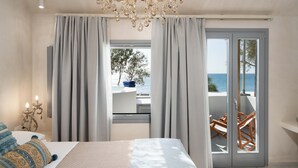 Une chambre à coucher avec un lit, un lustre, une fenêtre avec des rideaux et une vue sur la mer.