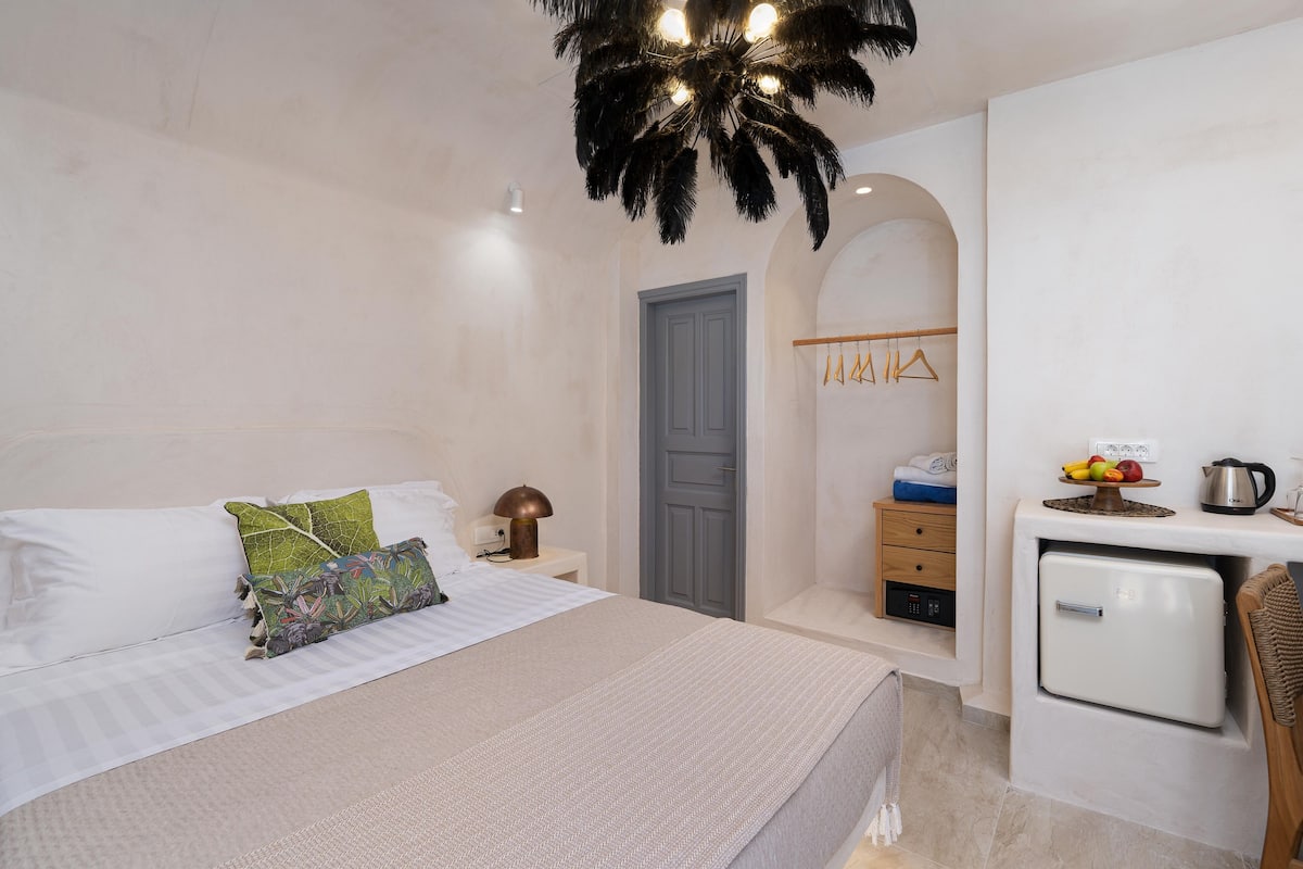 Un dormitorio con cama, mesita de noche, refrigerador pequeño y una silla de madera.