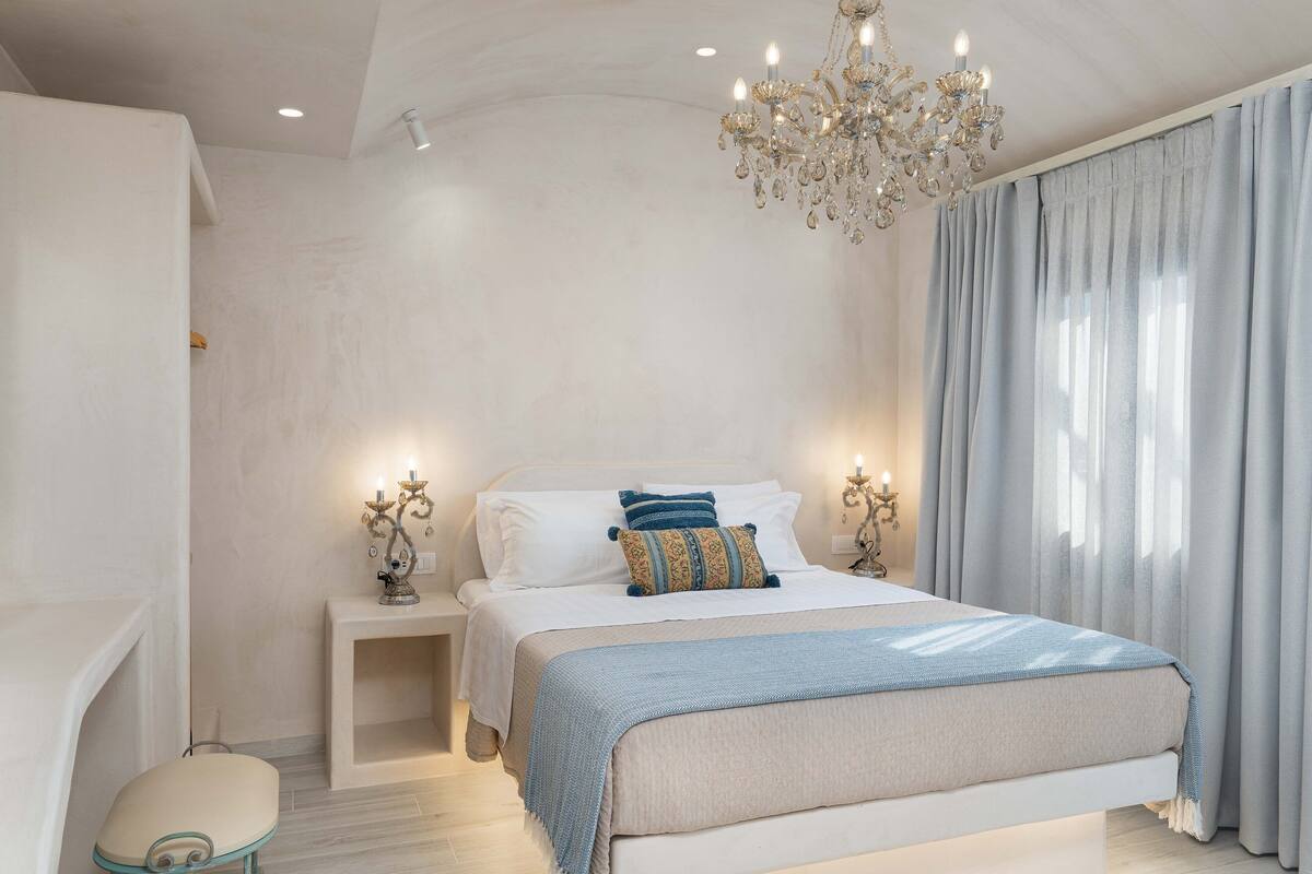 Un dormitorio con una cama grande, una araña y una mesita de noche con lámpara.