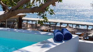 Une piscine avec deux serviettes enroulées, un arbre et une vue sur la mer.