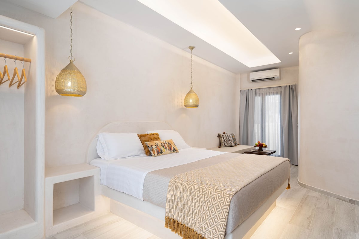 Un dormitorio moderno con una cama grande, mesitas de noche e iluminación colgante.